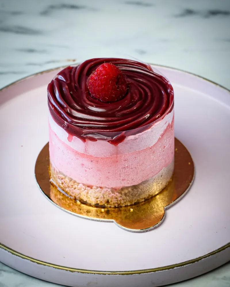 Pink mini cake with raspberry glaze and a fresh raspberry