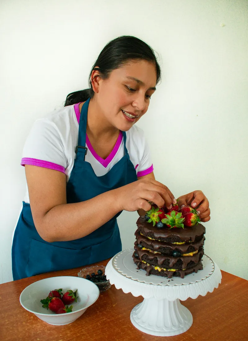Woman decorating a layered cake with fresh strawberries